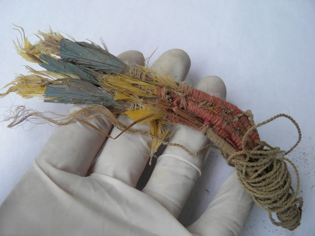 A bunch of feathers tied together in a white gloved hand