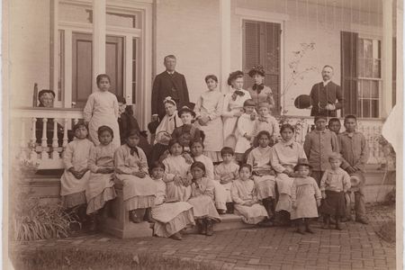 Richard Henry Pratt, founder of the Carlisle Indian Industrial School, poses alongside students around 1900.