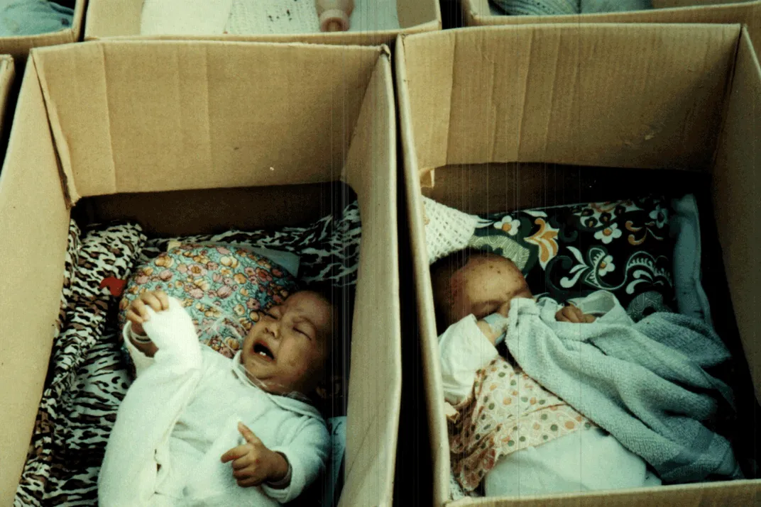 Two crying babies in boxes