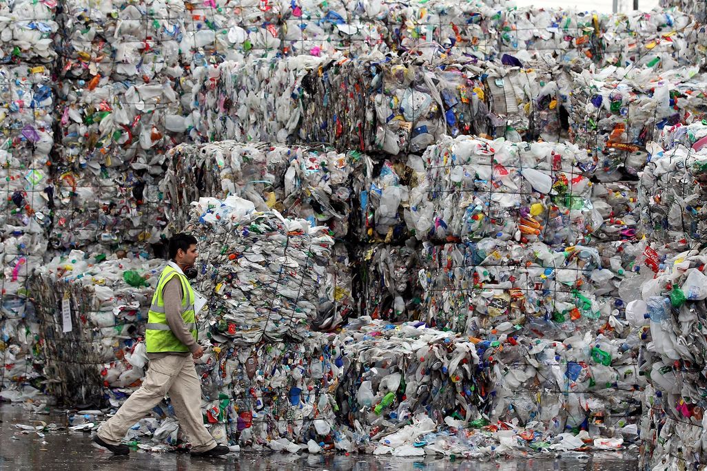 A person dwarfed by stacks of plastic bottles
