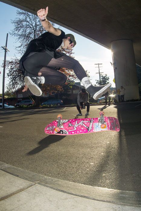 Girl doing kick flip over pink skateboard