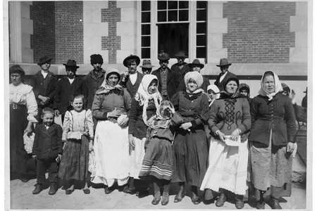 Immigrants outside a building on Ellis Island, circa 1900. 