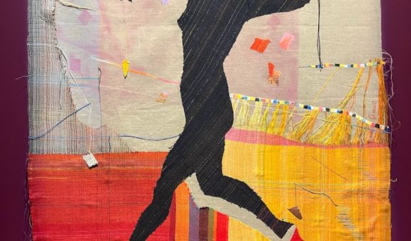 A black silhouette of a jumping woman against a colorful fabric background.