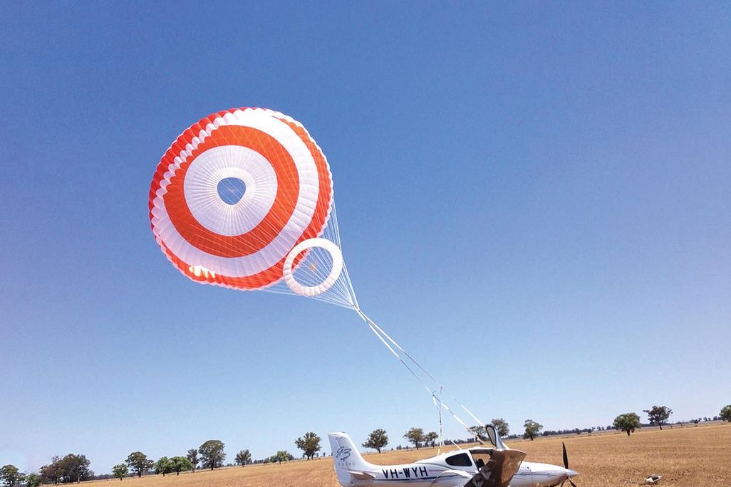 a parachute above a small aircraft only a bit above a field