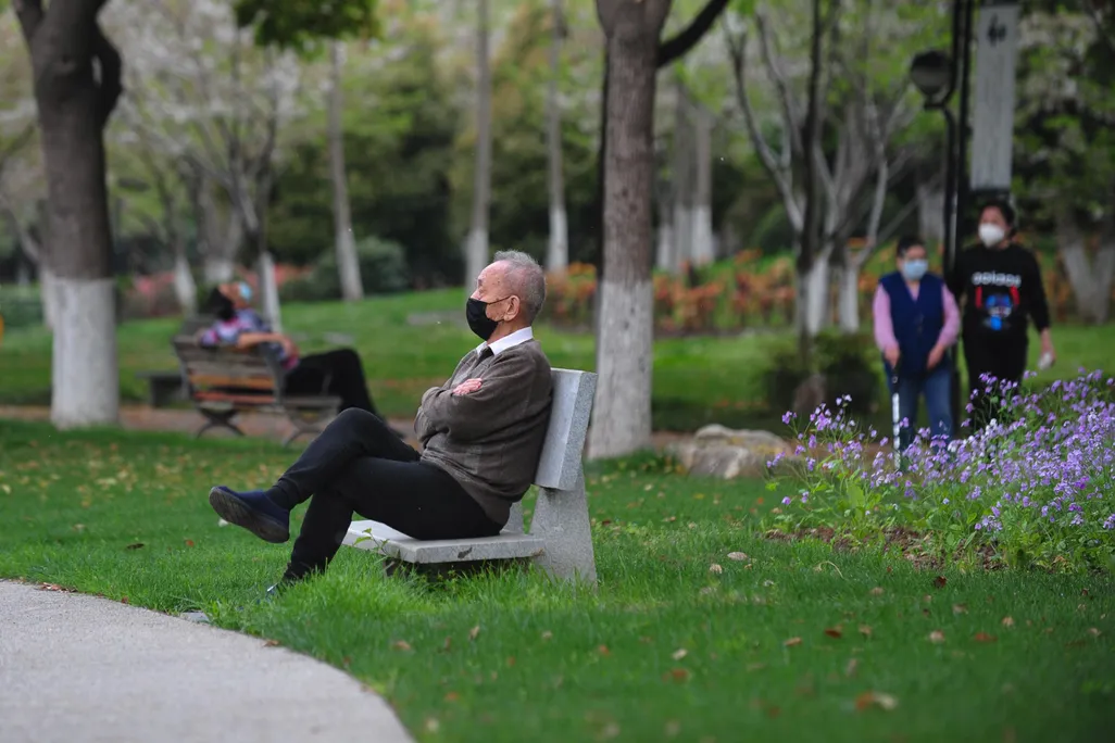 Elderly man rest on a bench after parks reopen in Wuhan on Thursday