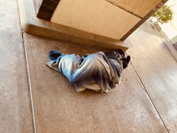 A homeless man sleeping on the sidewalk thumbnail