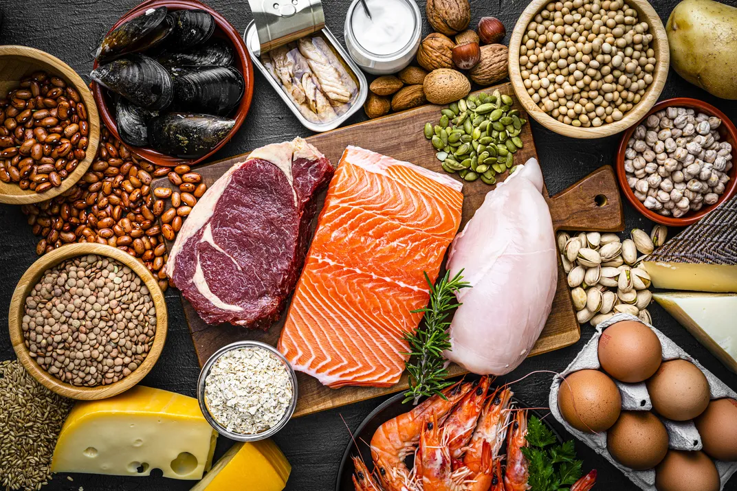 a table with a spread of protein sources, including meats, eggs, beans, nuts, seeds, seafood and cheese