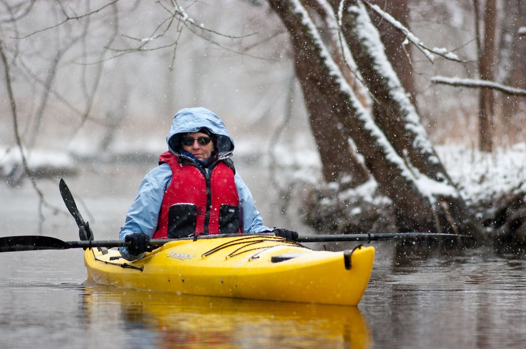 Kayaking in the Snow A woman glides across the water of Lake