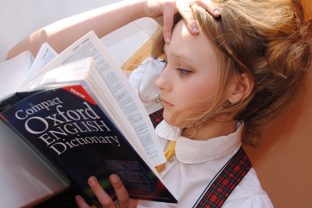 Girl with blonde hair reading Oxford English Dictionary