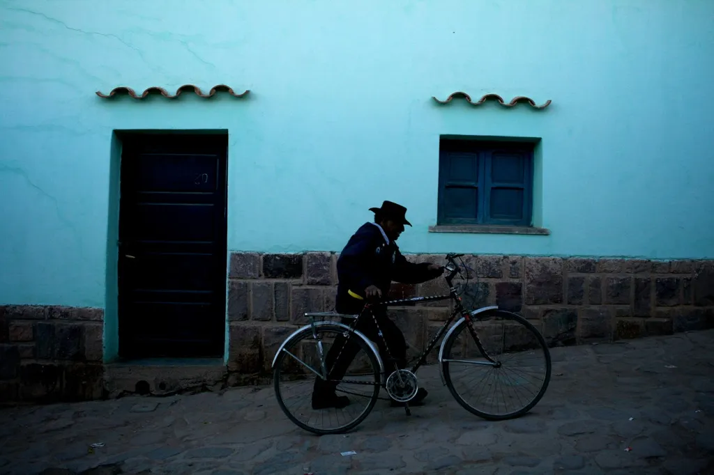 A man pushes his bike next to a blue house