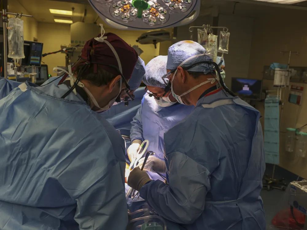 Doctors in scrubs gathered around a surgery table