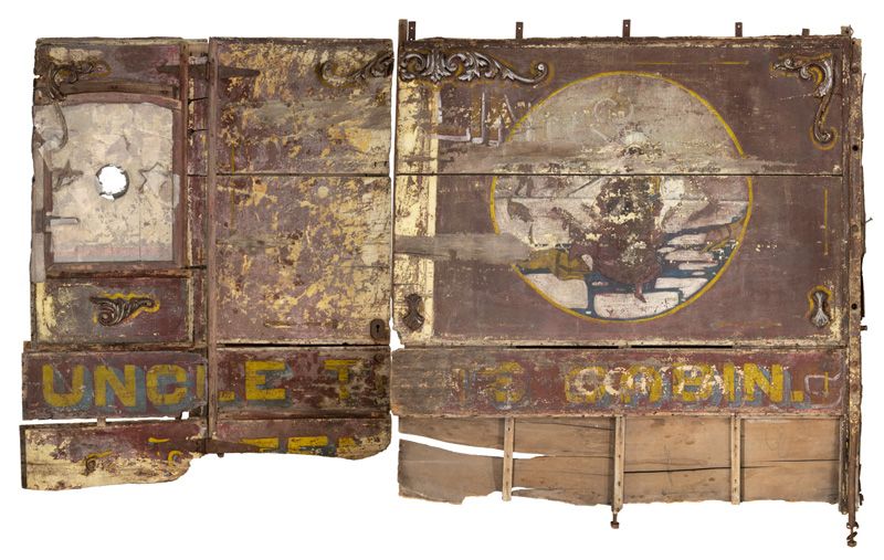 Wagon panels after conservation. The panel;s decoations include oa large piece of art, depicting the scene of Eliza and her child fleeing across the Ohio River, pursued by leaping dogs. Also visible are the words, printed in large yellow and blue font, “U