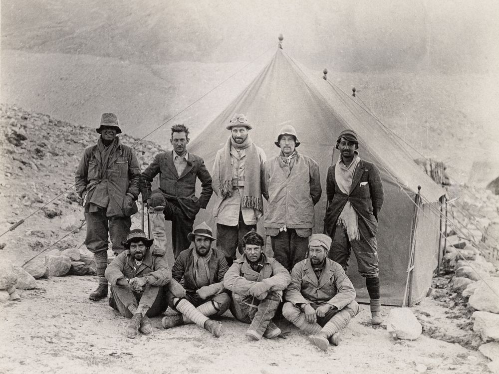 black and white photo of nine men in front of a tent