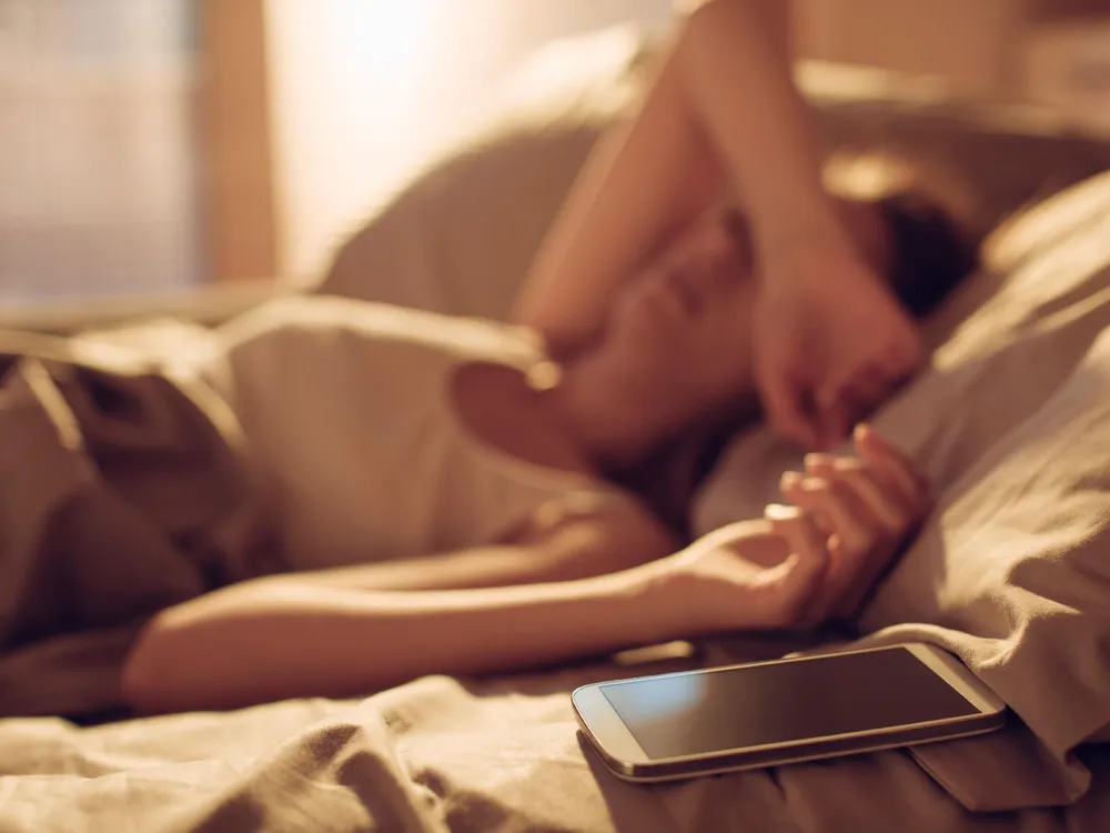 Woman in Bed Next to Smart Phone