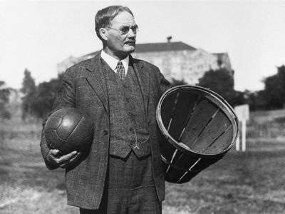 James Naismith, the inventor of basketball, holding a soccer ball and a basket
