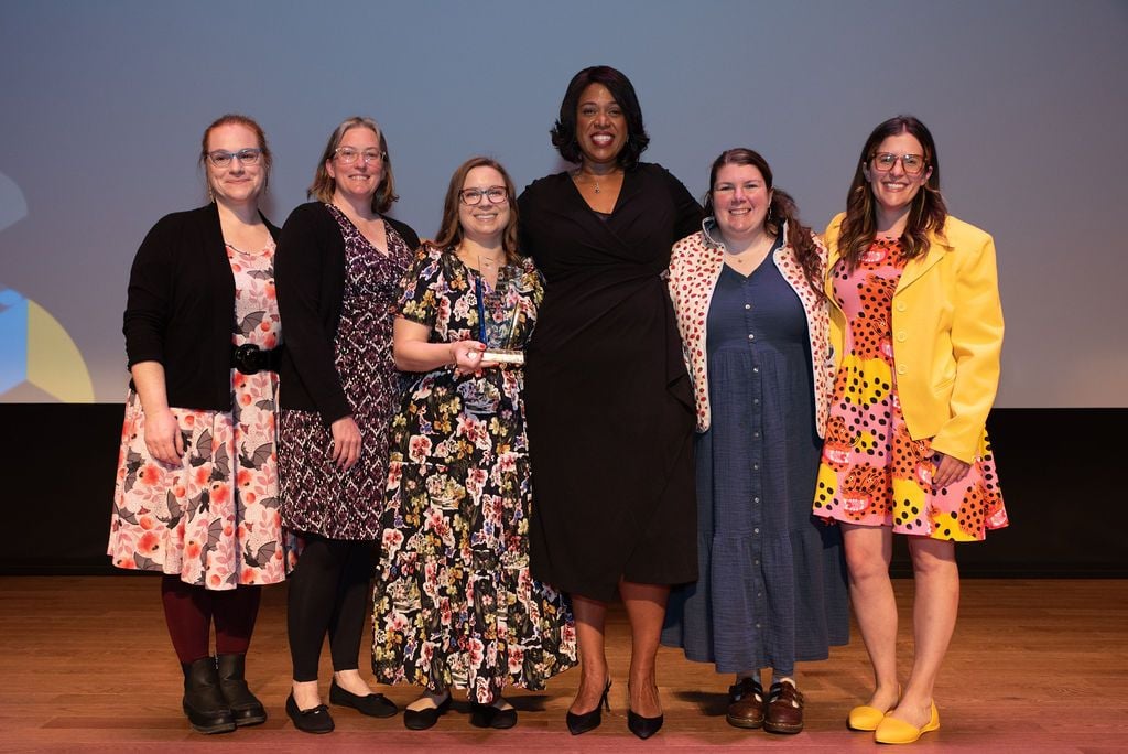 A group smiles with an award on stage