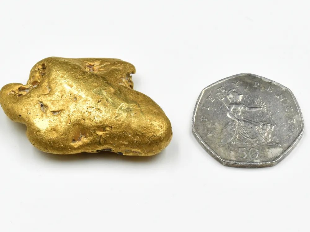 Gold nugget next to coin