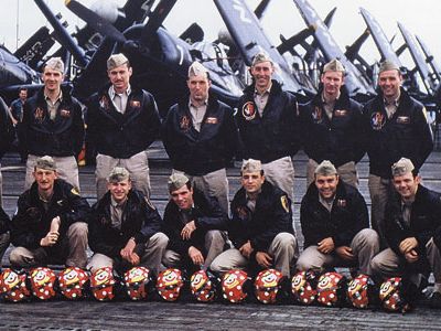 The squadron pilots pose on Valley Forge in July 1952, with 13 flight helmets for their fallen colleagues. Among the survivors are Cleland (back row, middle), Edinger (to his immediate left), and Balser (to Cleland’s right).