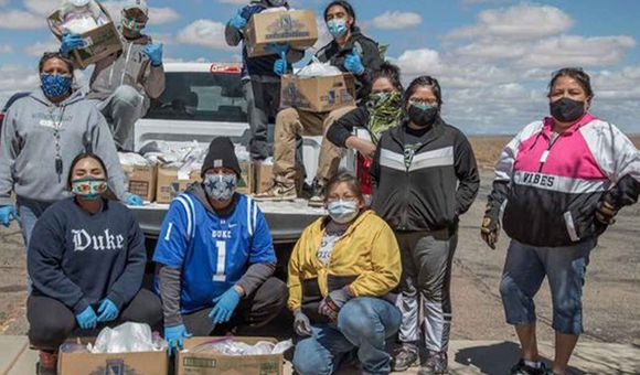 Volunteers with the Navajo & Hopi Families Covid-19 Relief Fund distribute food and other essential supplies to isolated communities and farmsteads on the Navajo Nation and Hopi Reservation. As part of the Smithsonian's virtual program 24 Hours in a Time of Change, Shandiin Herrera (Diné)—seated on the left, wearing a Duke University sweatshirt—describes how this grassroots response to the COVID-19 pandemic came together last spring and shares her experiences as the fund's volunteer coordinator in Monument Valley, Utah. (Photo by Karney Hatch) 