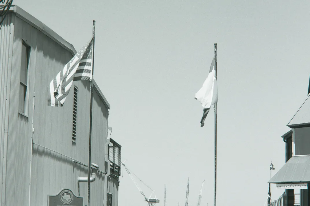 The flags of the U.S. and Texas fly near the Battle of Galveston historical marker