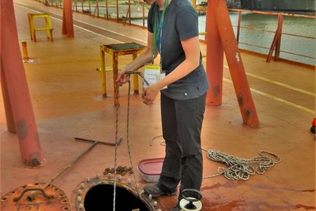 The author lowers a net into a topside ballast water tank to sample marine plankton and zooplankton