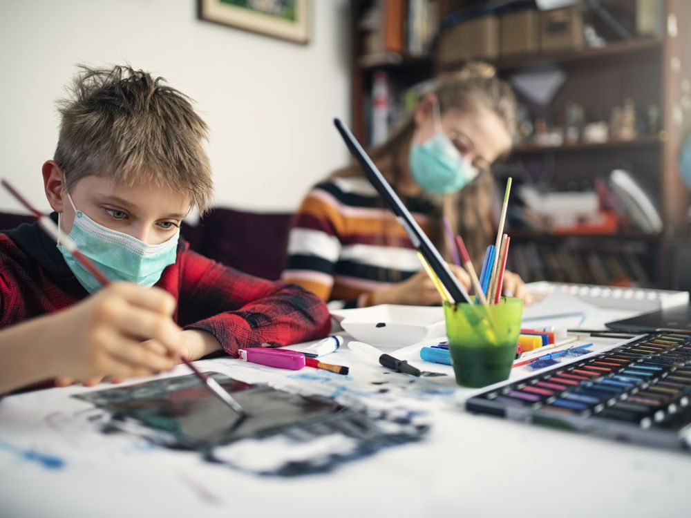 Image shows two children wearing masks painting