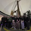 A group smile in front of the Great Refractor telescope