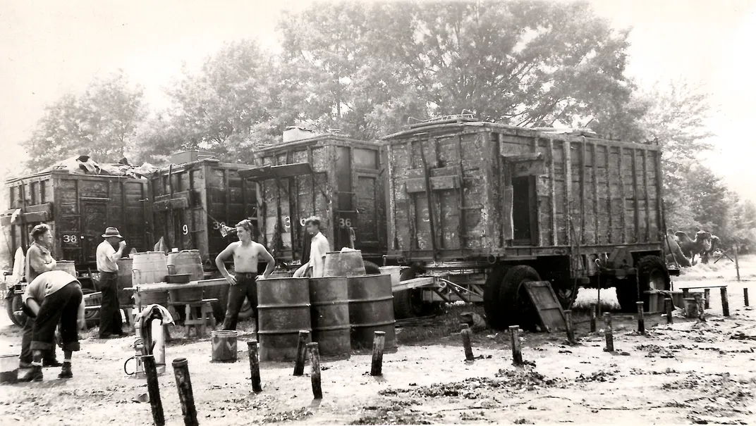 Circus staff standing next to charred wagons