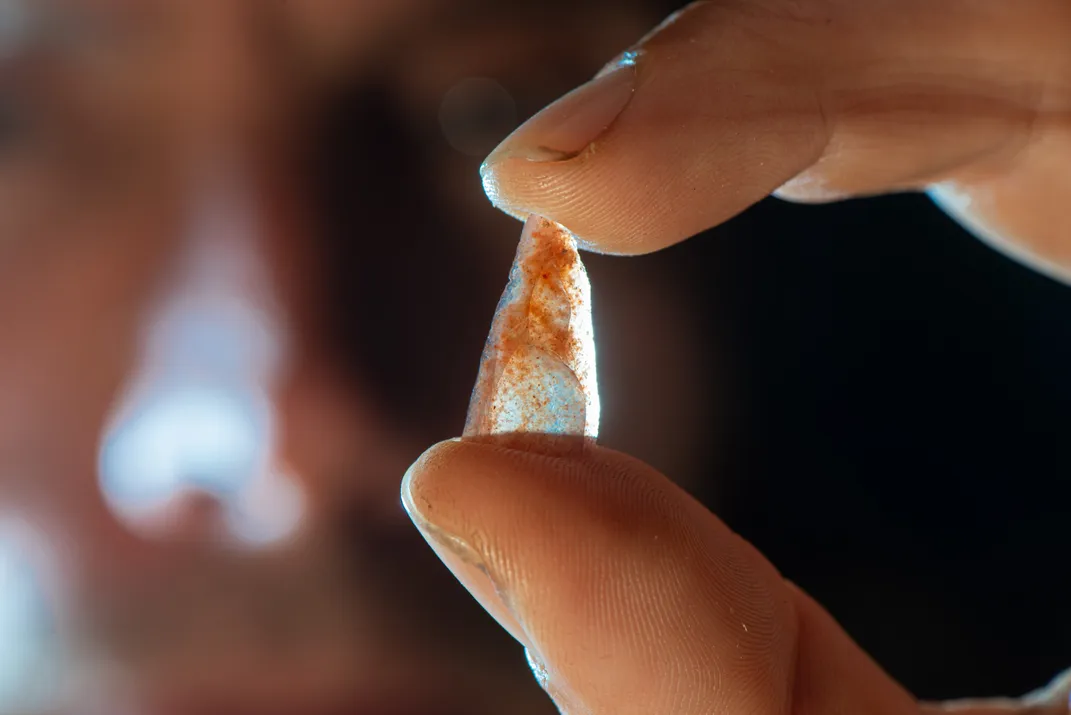 Hand holding up a small triangular stone point