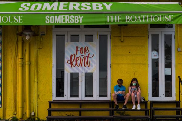 Two teenagers sit in front of a closed bar in Stanley thumbnail