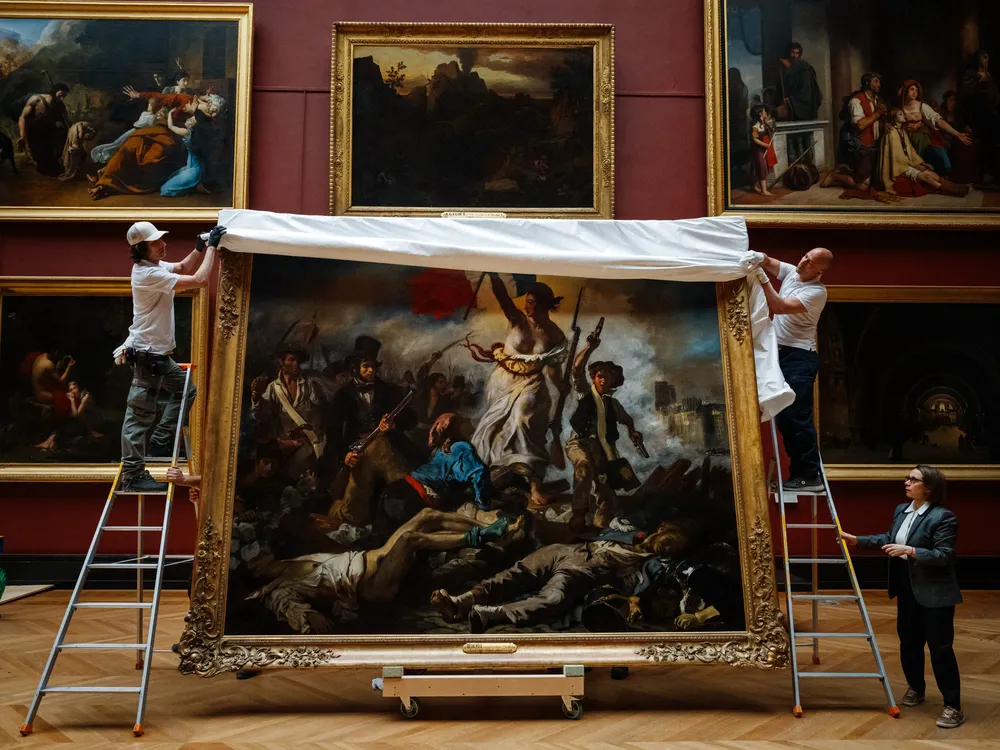 Workers taking protective sheet off a painting in an art gallery