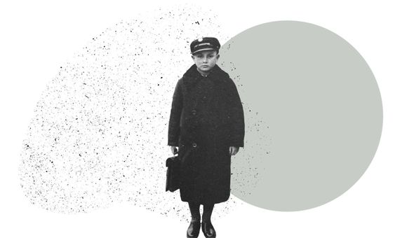 A boy in a long wool coat and hat holds a small case