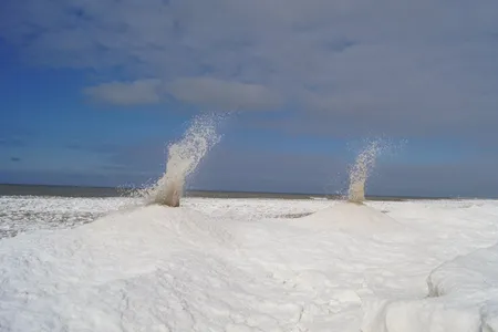 On Sunday, a National Weather Service employee snapped a photo of two ice volcanoes erupting on the shores of Lake Michigan.