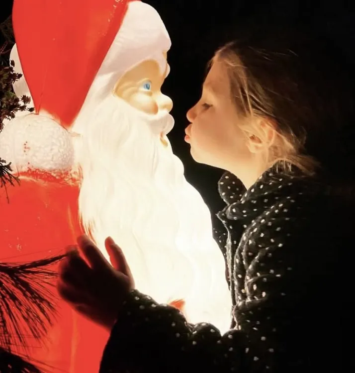 A young girl kiss a Santa Claus statue