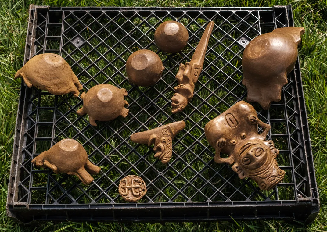 brown pottery sitting on a rack ready for firing