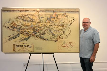 Mike Van Eaton of Van Eaton Galleries, posing with Disney's early map of Disneyland