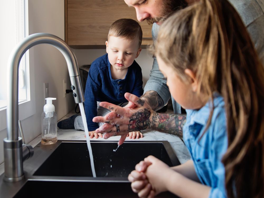 father teaching children how to wash their hands