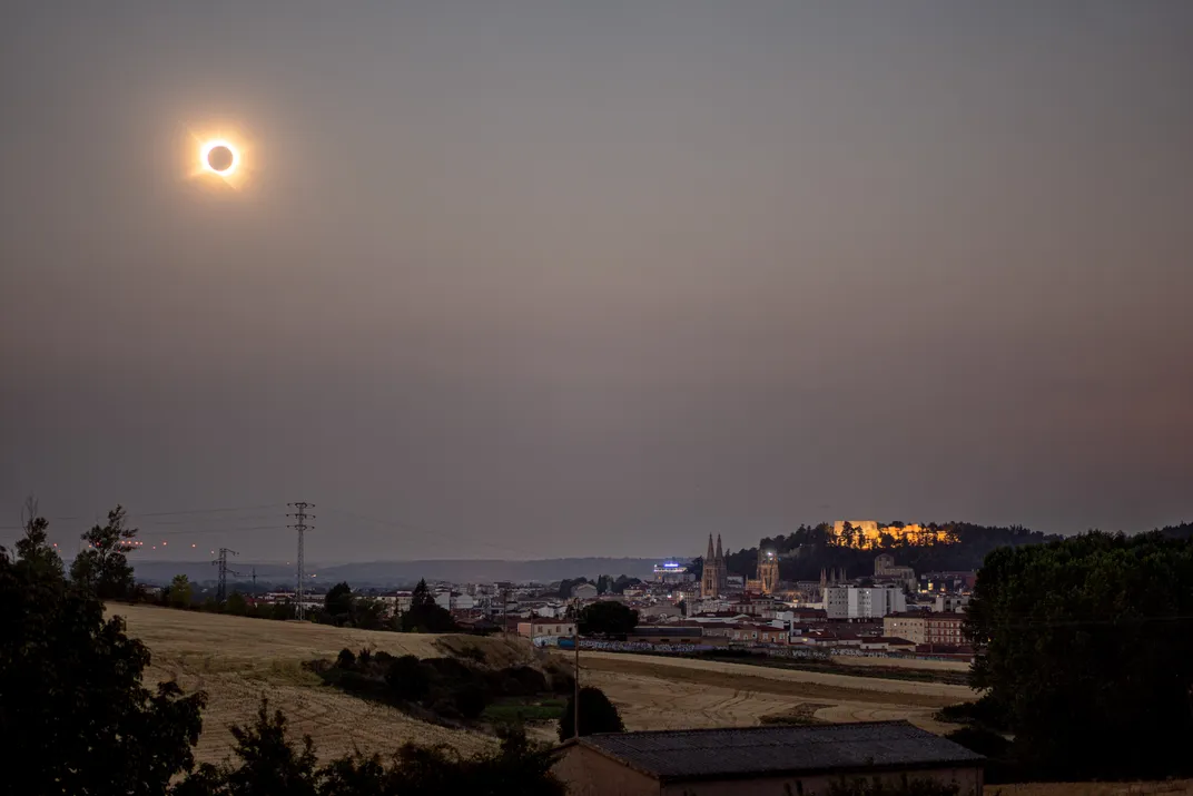 an eclipsed sun in the sky over telephone wires and buildings