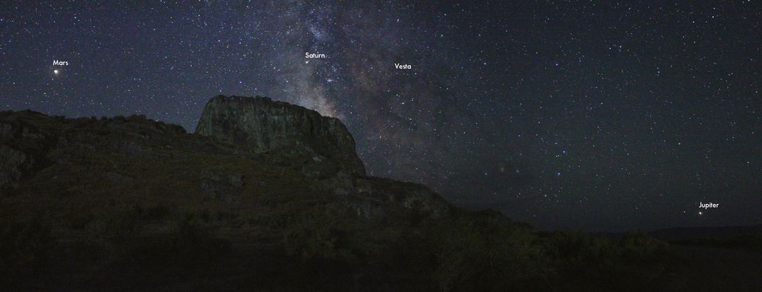 A view of mountains with stars behind, with Mars, Saturn, Vesta and Jupiter labeled from left to right