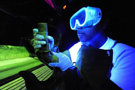 Senior Airman Lilia Linares uses a fluorescent magnetic particle process to inspect an aerospace ground equipment hook for cracks May 27 at Charleston Air Force Base S.C. The nondestructive inspection section inspects more than 40,000 pieces of weapon systems and non-weapon systems assets a year. Airman Linares is a nondestructive inspection journeyman with the 437th Maintenance Squadron. (U.S. Air Force photo/James M. Bowman)