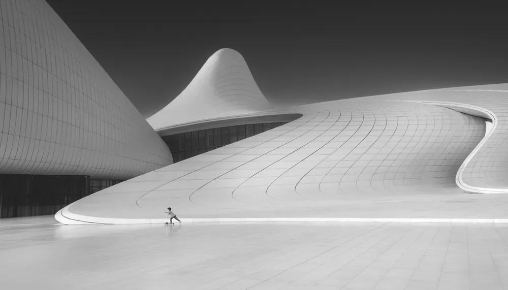 A child rides a scooter across the plaza of the flowing lines of the Heydar Aliyev Center. The design by the late Zaha Hadid, was meant to break from the rigid forms prevalent in most of Baku's Soviet legacy architecture, and bring a more playful and gentle tone to the city.