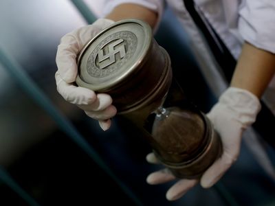 A member of the federal police holds an hourglass with Nazi markings, one of the 75 Nazi artifacts seized from an Argentinian house this June.