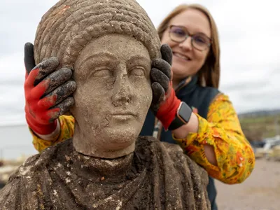Archaeologist Rachel Wood holds a Roman bust found at the site of a Norman church.
