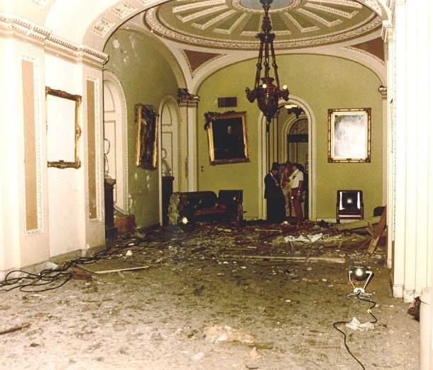 A hazy view of the interior of an elegant room, with curved ceilings and debris scattered across the floor; portraits hanging on wall are tilted and damaged