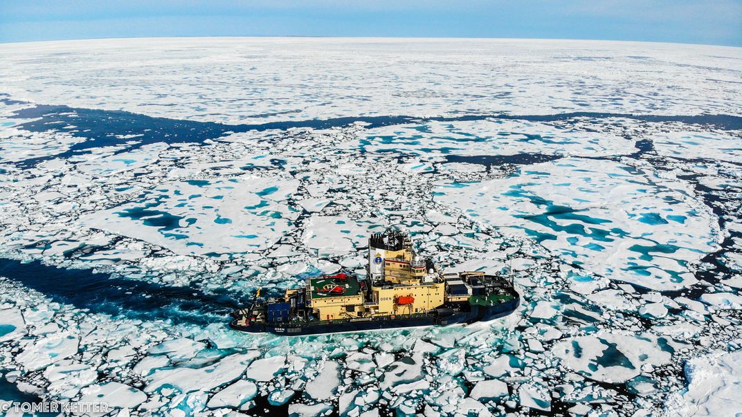 A boat in water with ice sheets floating around it.