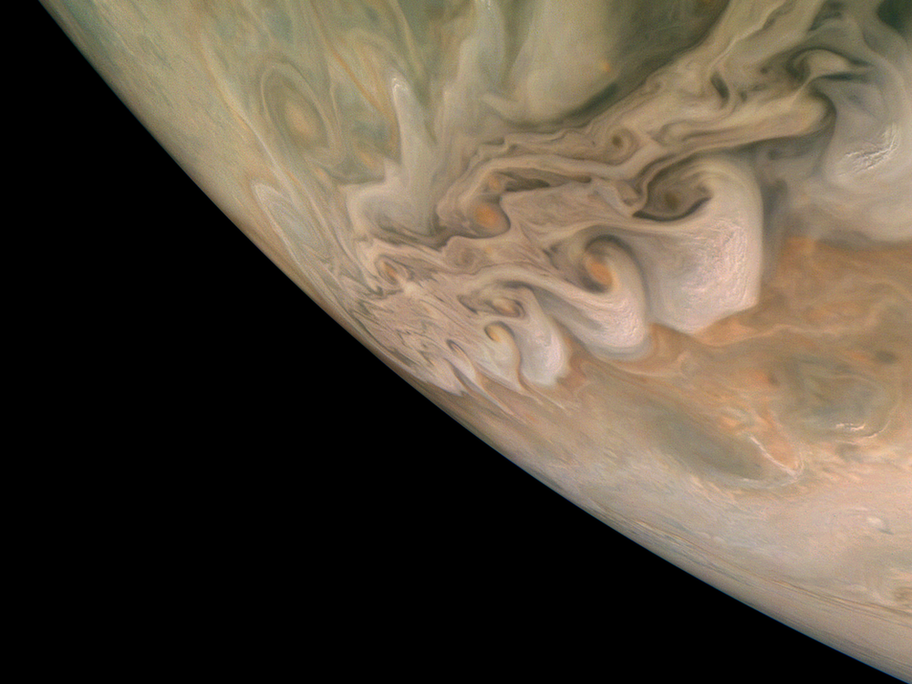 A photograph of Jupiter's swirling clouds and the curve of the planet's horizon