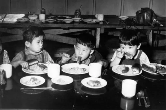 Black and white photo of three children eating