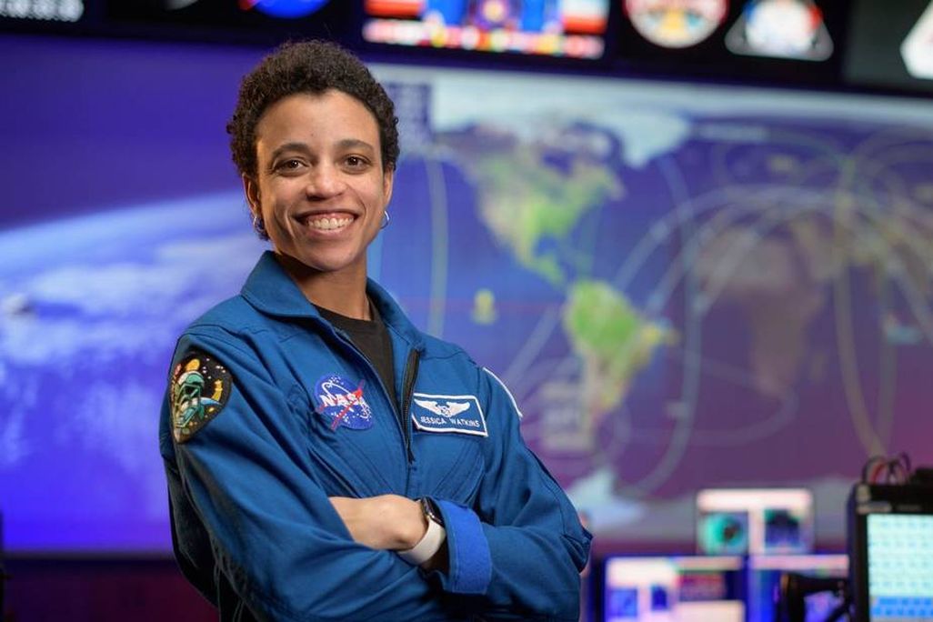 An image of Jessica Watkins, standing and smiling proudly at the camera. She has short cropped hair.