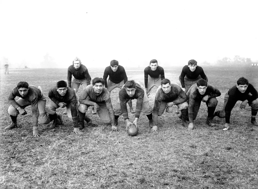 The 1912 Carlisle Indian Industrial School football team posed in two rows as if about to make a play.
