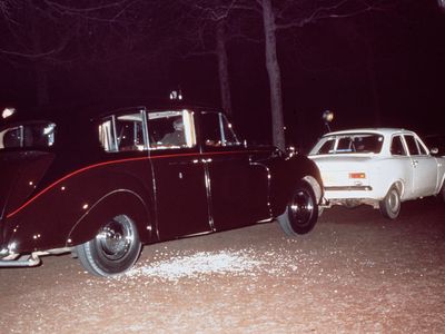 The aftermath of Ian Ball&#39;s attempt to kidnap Princess Anne. Ball&#39;s white Ford Escort is parked blocking the path of the princess&#39; limousine.